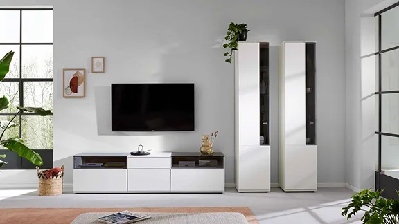 Helle Wohnwand-Kombination von Interliving mit weißem TV-Lowboard, zwei Vitrinenschränken und Wand-TV.